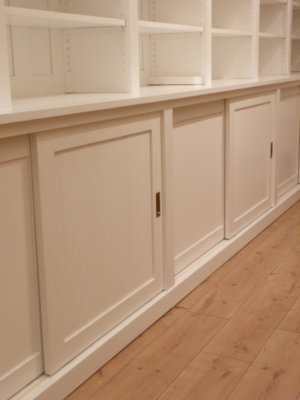 Bücherwand mit Schiebetüren, Erle Massivholz, weiss lasiert Bücherwand mit Schiebetüren, Erle Massivholz, weiss lasiert